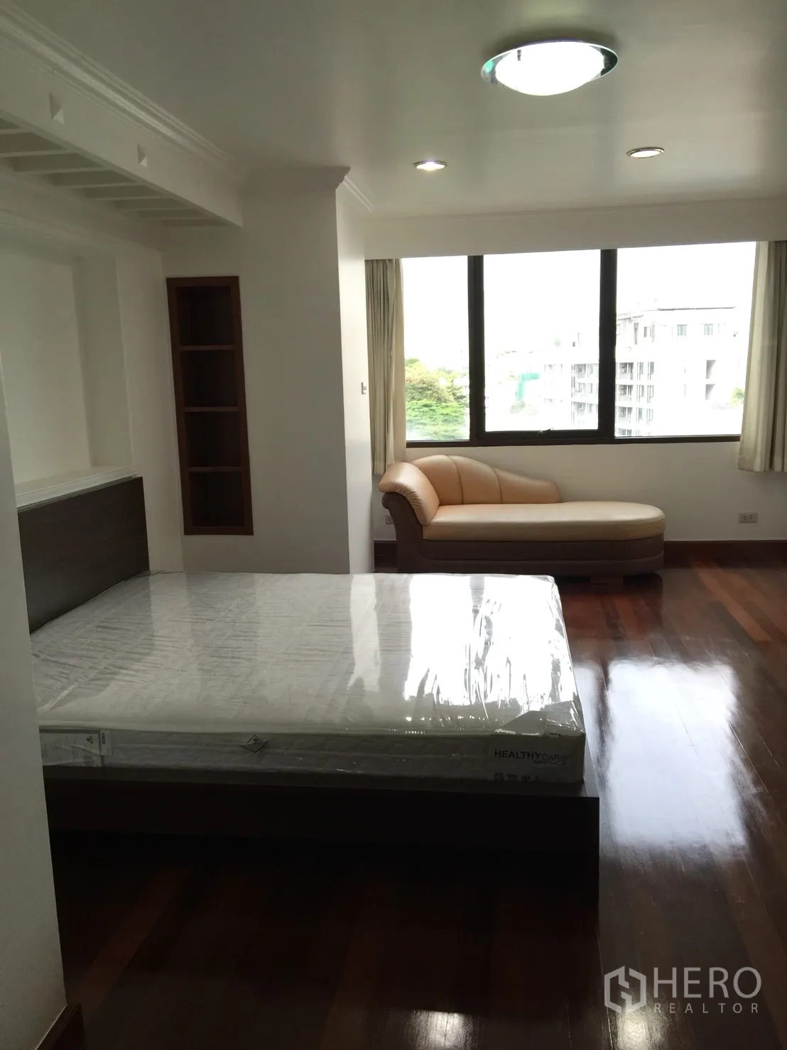 Condominium for rent or sale in Watthana, Bangkok - Bedroom featuring a double bed, chaise lounge and large window with city views.