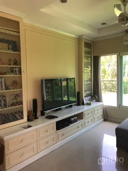 Detached House for sale in Pak Kret, Nonthaburi - Bright living area with built-in TV cabinet and large window facing the garden.