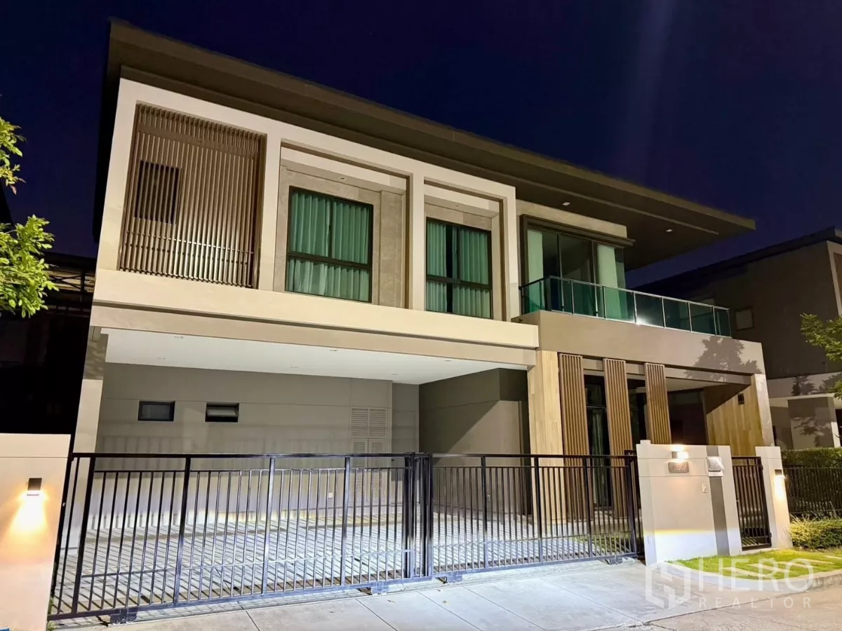 Detached House for rent in Bang Phli, Samut Prakan - Two-storey modern detached house at night with gated driveway and glass balcony.