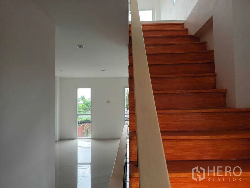 Shophouse for sale in Bueng Kum, Bangkok - Close-up of wide wooden stairs leading to bright upper levels.