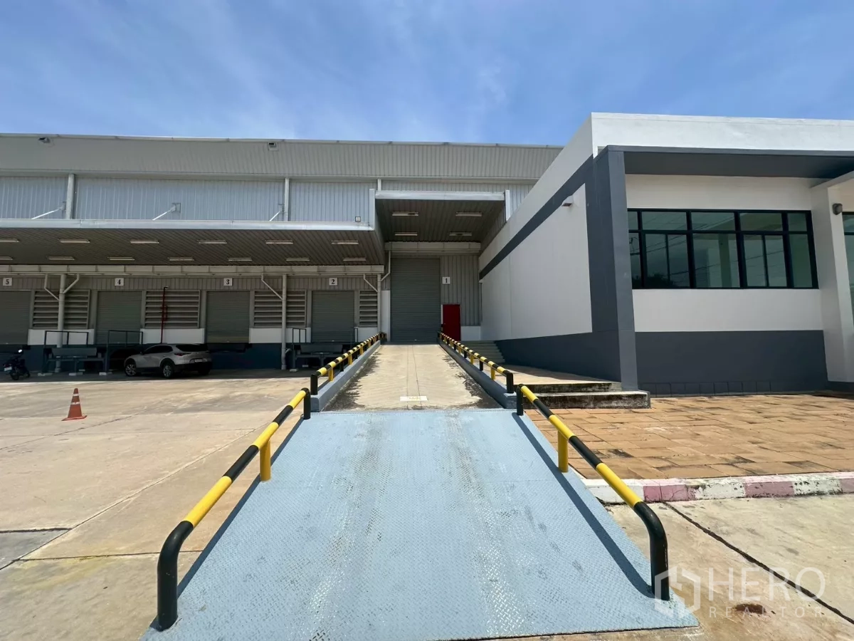 Warehouse for rent in Bang Phli, Samut Prakan - Steel ramp with safety rails connecting to dock door next to glass-front office.