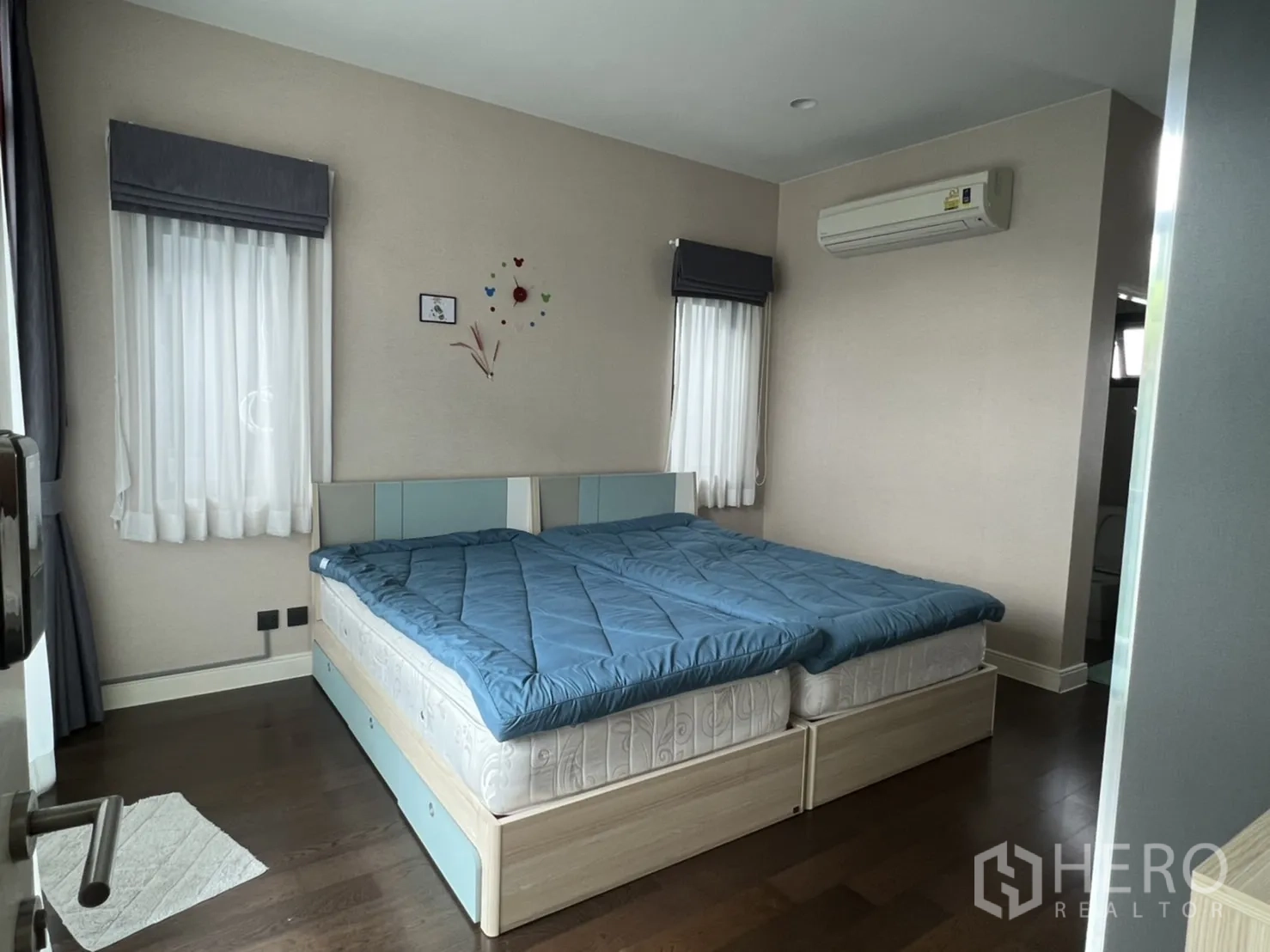 Detached House for rent or sale in Bang Kapi, Bangkok - Cozy bedroom with twin bed setup, corner windows, curtains and wall-mounted air conditioner.