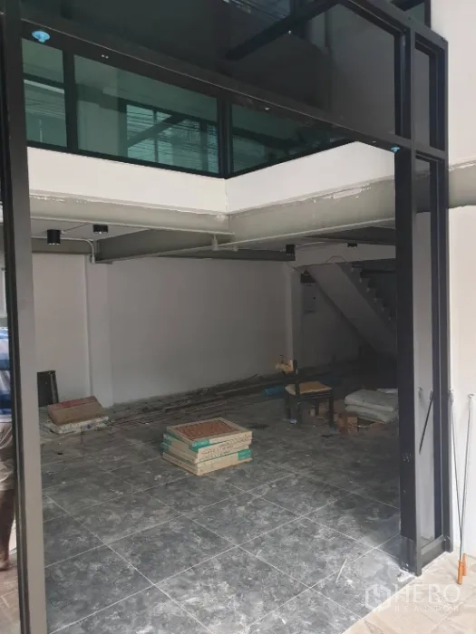 Office Space for rent in Khlong Toei, Bangkok - Ground-floor open-plan space with glass mezzanine and tiled flooring under renovation.