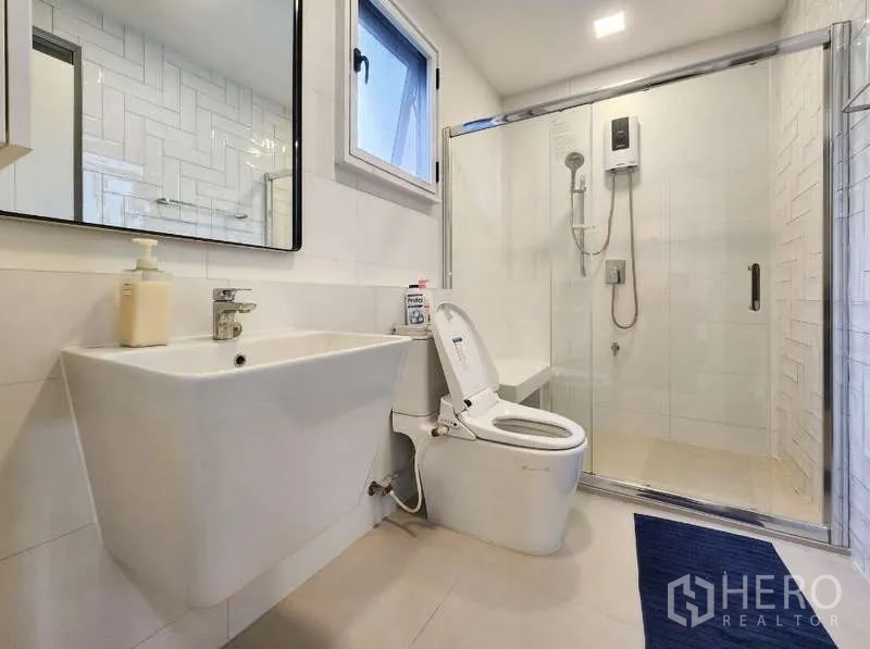 Detached House for rent or sale in Prawet, Bangkok - Contemporary bathroom with glass-enclosed shower, window and white sanitary ware.