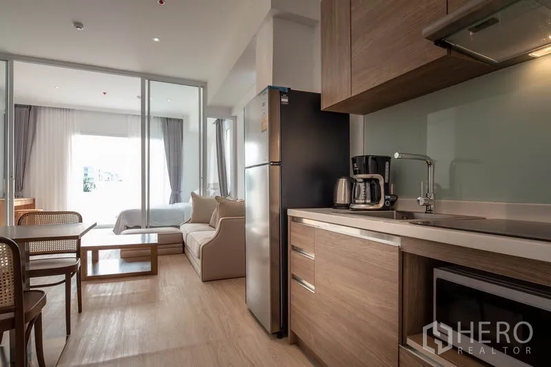 คอนโด ให้เช่าในKhlong Toei, Bangkok - ครัวขนาดกะทัดรัดตู้ไม้ ชุดโต๊ะทานอาหาร และประตูกระจกบานเลื่อนเชื่อมสู่ห้องนอน