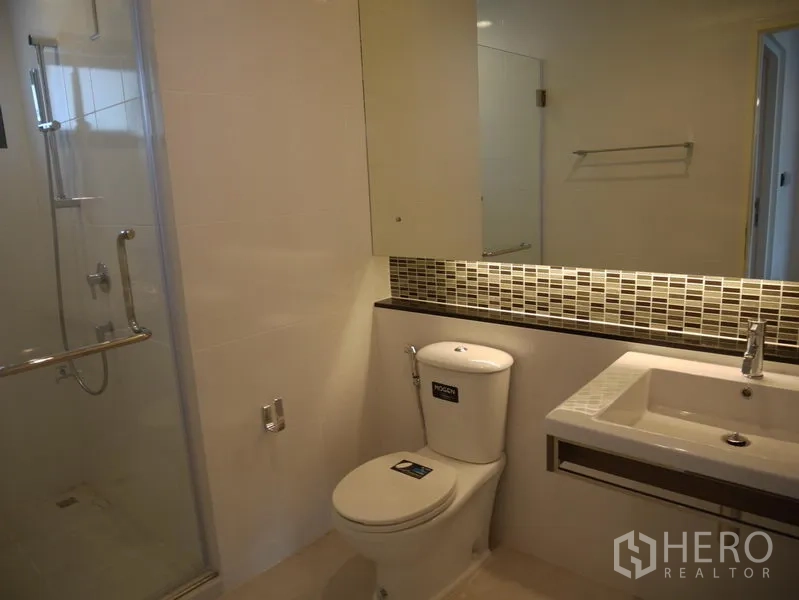 Detached House for rent in Bang Kapi, Bangkok - Modern bathroom with glass shower enclosure, long vanity, mirror and mosaic backsplash.