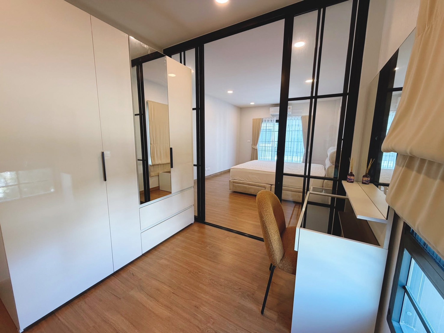 独立式住宅 出租在Bang Phli, Samut Prakan - 衣帽间以黑框玻璃与卧室相连，亮面衣柜与小书桌。