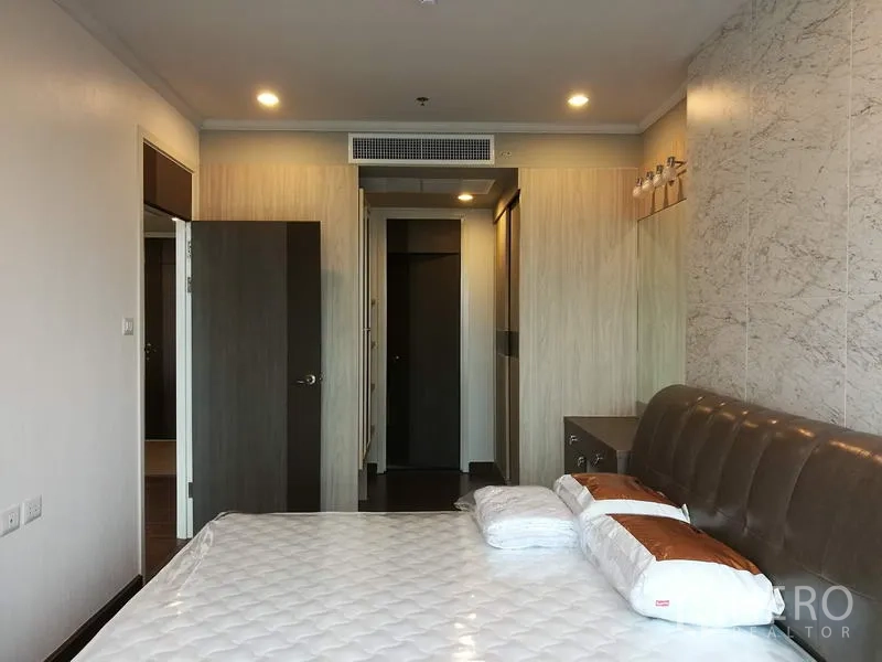 Condominium for rent in Sathon, Bangkok - Bedroom view toward the doorway with built-in wardrobes, recessed lighting and warm wood finishes.