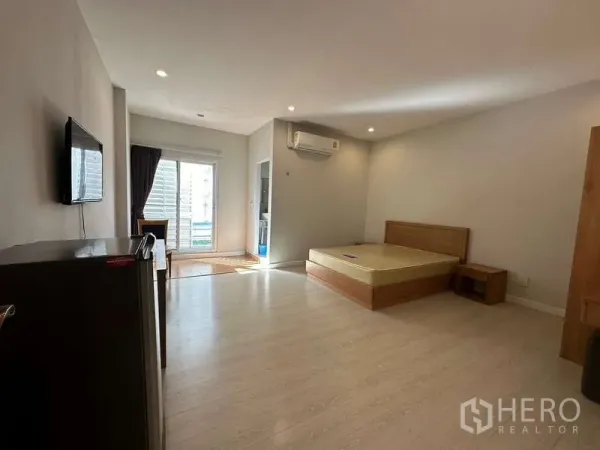 Home Office for rent in Chatuchak, Bangkok - Bright bedroom with bed, balcony doors, air conditioner and wall-mounted TV.