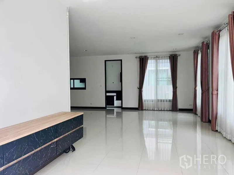 Detached House for rent or sale in Thanyaburi, Pathum Thani - Bright open-plan living room with glossy tile floors, large windows and curtains in a detached house.
