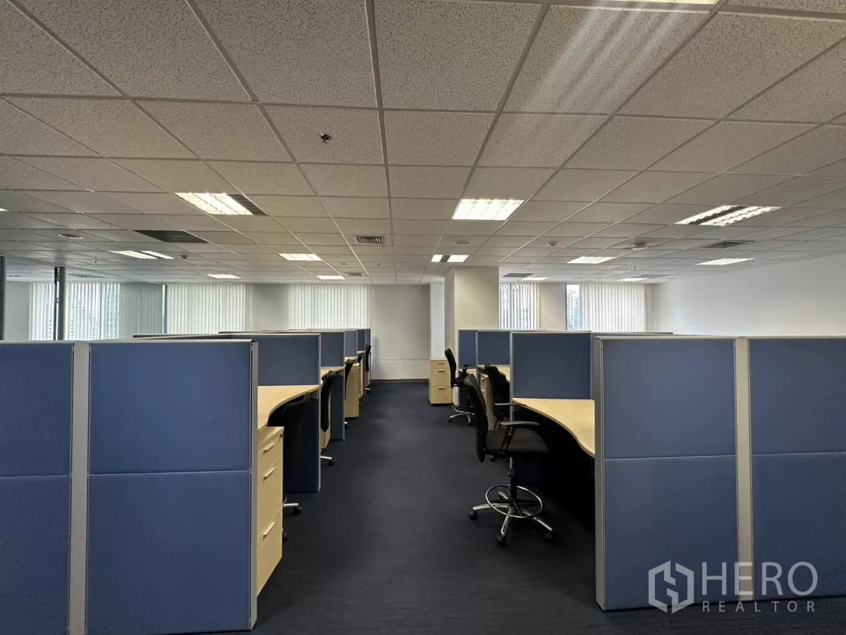 Office Space for rent in Watthana, Bangkok - Central aisle between blue-partitioned workstations under grid ceiling lights.
