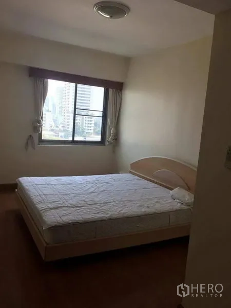 Condominium for rent in Watthana, Bangkok - Third bedroom with window city view, queen bed, and neutral decor.