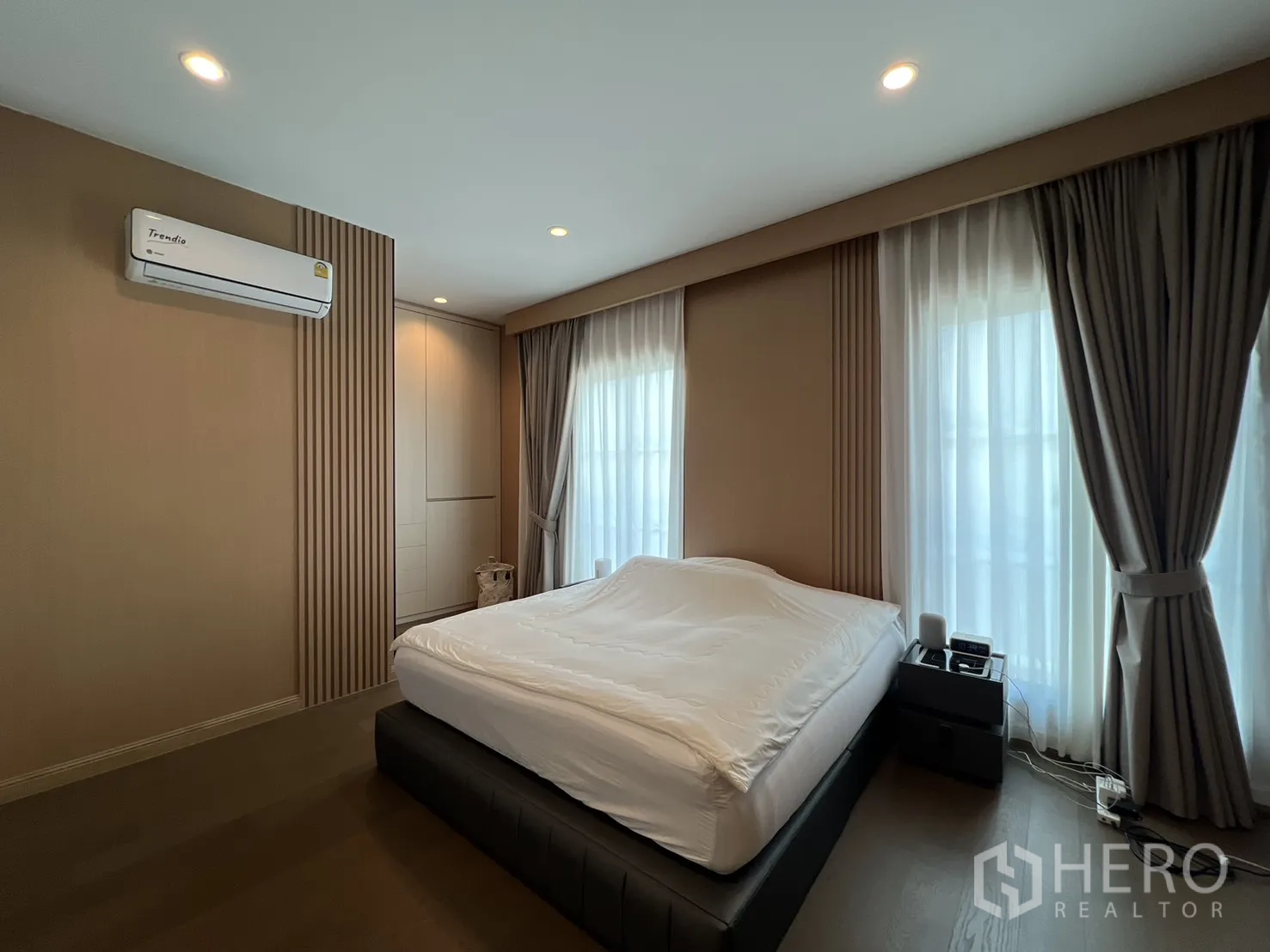 Detached House for rent or sale in Mueang Pathum Thani, Pathum Thani - Bright corner bedroom with windows on two sides and neutral decor.
