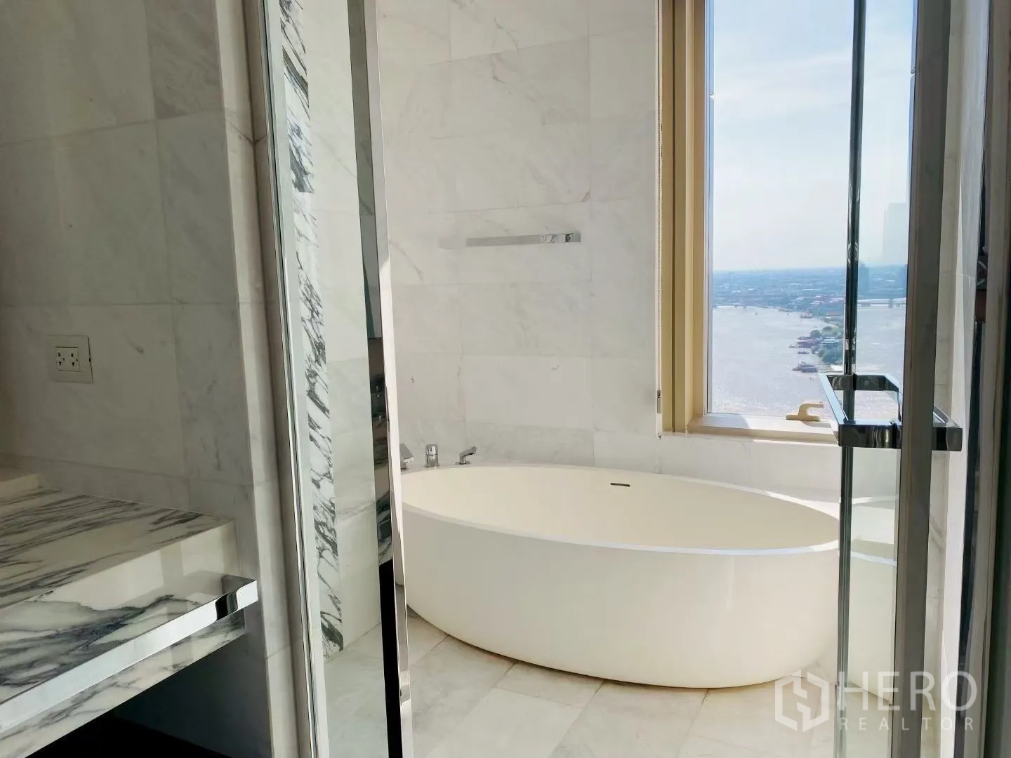 คอนโด for rent in Sathon, Bangkok - ห้องน้ำหินอ่อนพร้อมอ่างอาบน้ำทรงรีข้างหน้าต่างเห็นวิวแม่น้ำ และห้องอาบน้ำกระจก