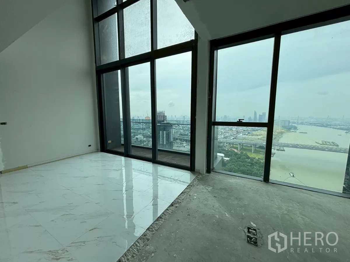 Condominium for sale in Bang Kho Laem, Bangkok - Corner room with double-height glass and a balcony showcasing panoramic river and city skyline views.