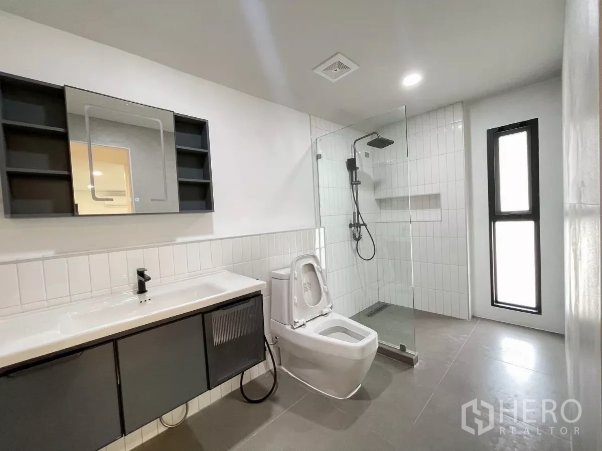 独立式住宅 出售在Prawet, Bangkok - 宽敞浴室，雨淋花洒、悬空浴柜与高窗采光。