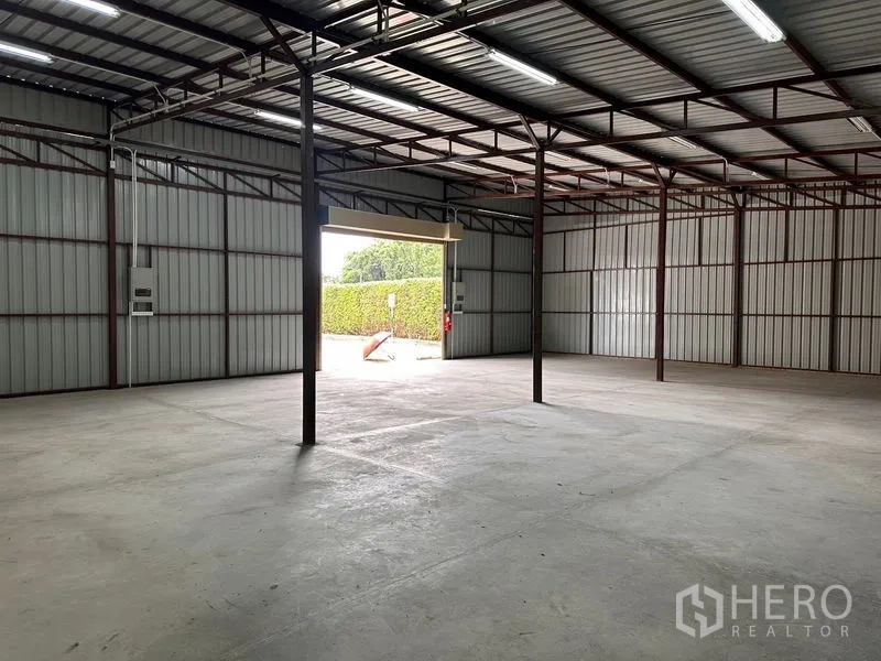 Warehouse for rent in Mueang Nonthaburi, Nonthaburi - Interior view toward loading door showing ample floor space and electrical panels mounted on the wall.