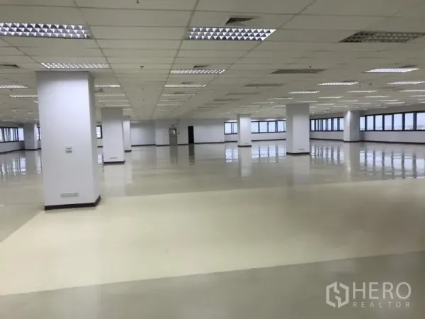 Office Space for rent in Bang Na, Bangkok - Expansive open-plan office floor in Bang Na with white columns, reflective flooring, drop ceiling lighting and wide perimeter windows.