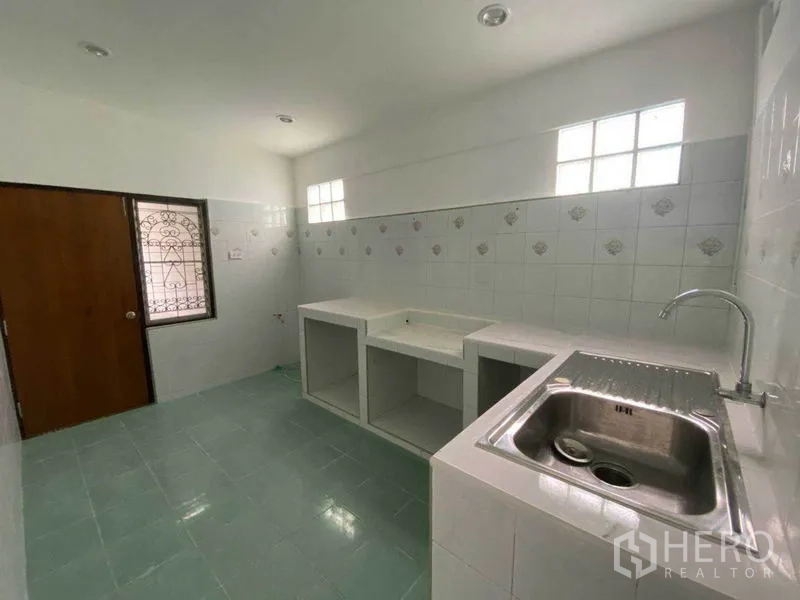 Detached House for rent in Huai Khwang, Bangkok - Bright tiled kitchen with built-in counter space and stainless sink.