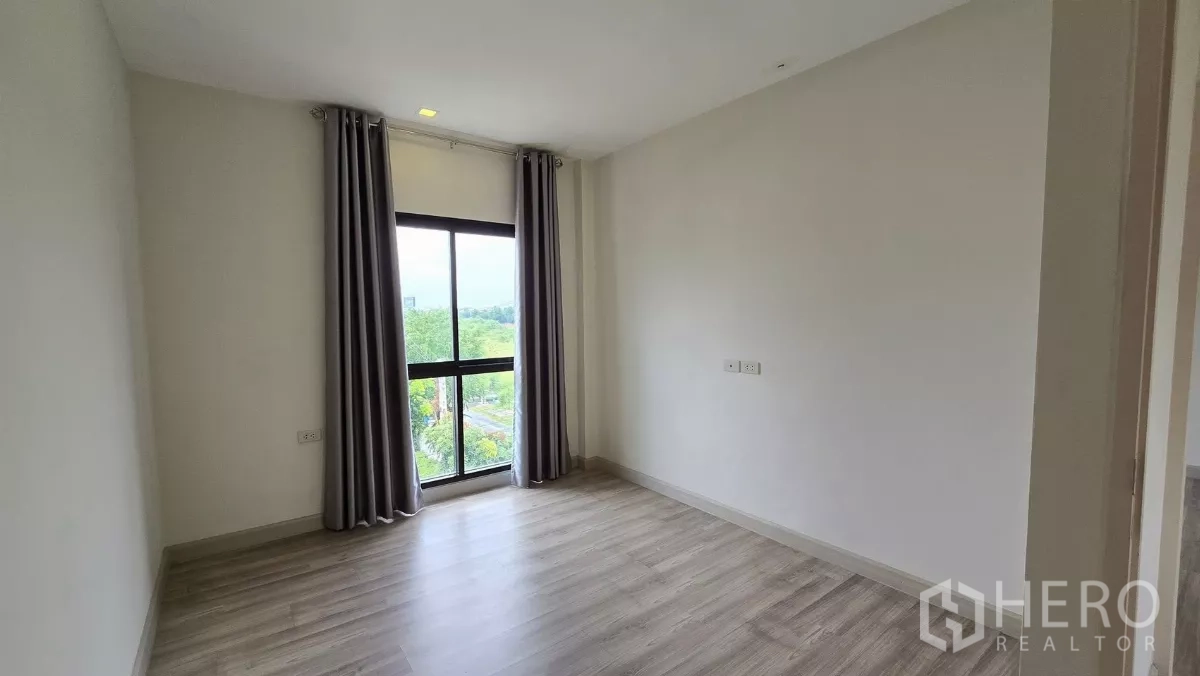 Townhouse for rent or sale in Saphan Sung, Bangkok - Bedroom with floor-to-ceiling window offering green neighborhood views.