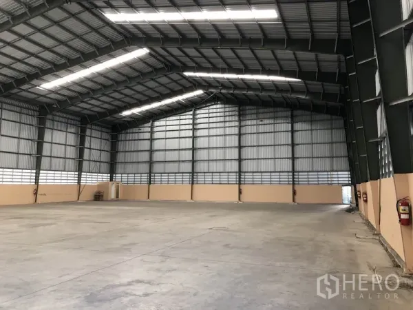 Warehouse for rent in Pathum Thani - Clear-span warehouse interior with high steel truss roof, daylight panels and smooth concrete floor.