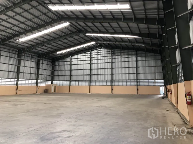 Warehouse for rent in Pathum Thani - Clear-span warehouse interior with high steel truss roof, daylight panels and smooth concrete floor.