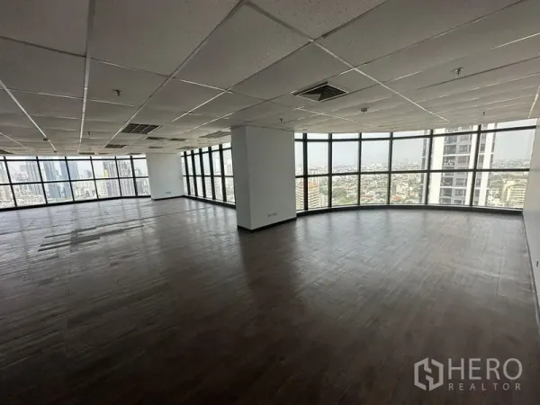 Office Space for rent - Corner office area with curved floor-to-ceiling windows offering a panoramic city view.