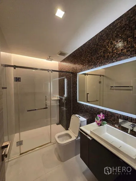 Condominium for rent - Contemporary bathroom with glass shower, mosaic feature wall and backlit mirror.