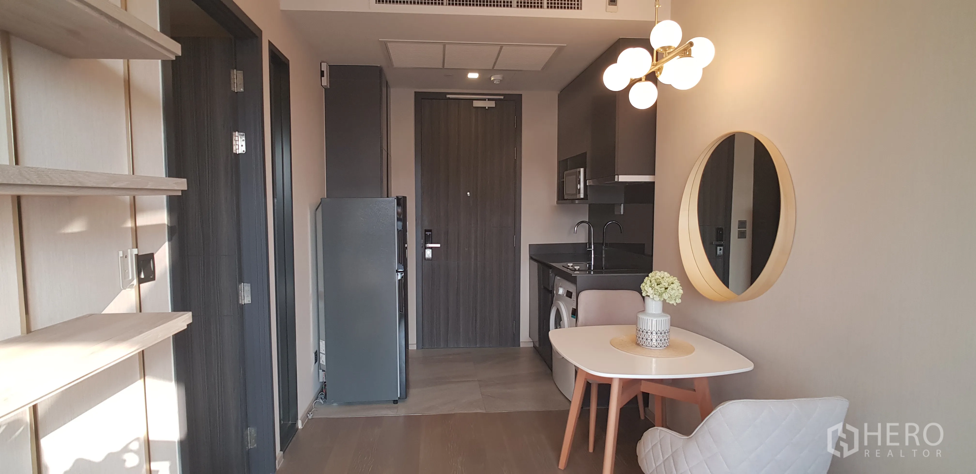 Condominium for rent in Watthana, Bangkok - Entry hallway facing the kitchenette, refrigerator and floating shelves in a modern condo.