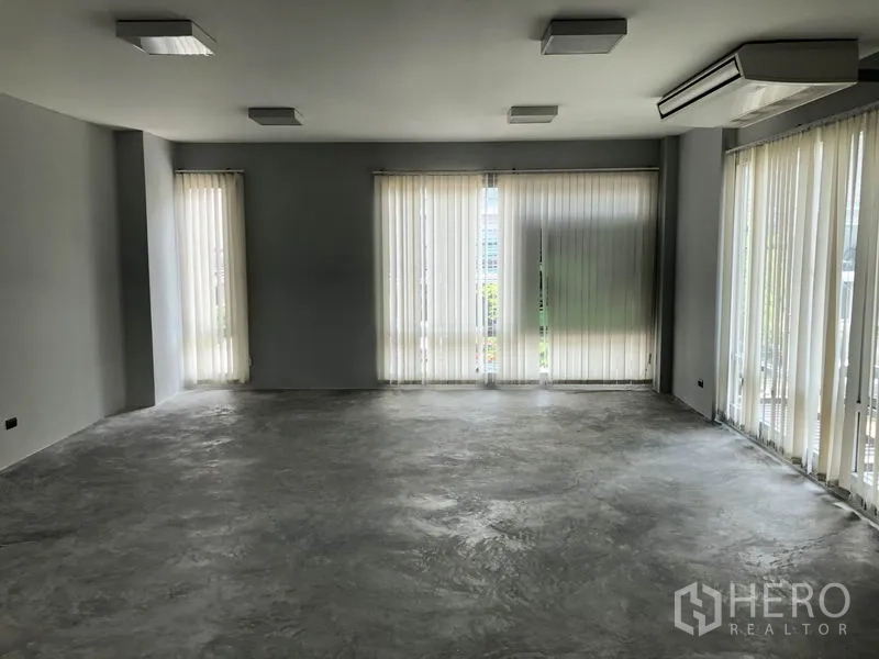 Home Office for rent in Wang Thonglang, Bangkok - Large open-plan floor with tall windows, vertical blinds, and ceiling lights.