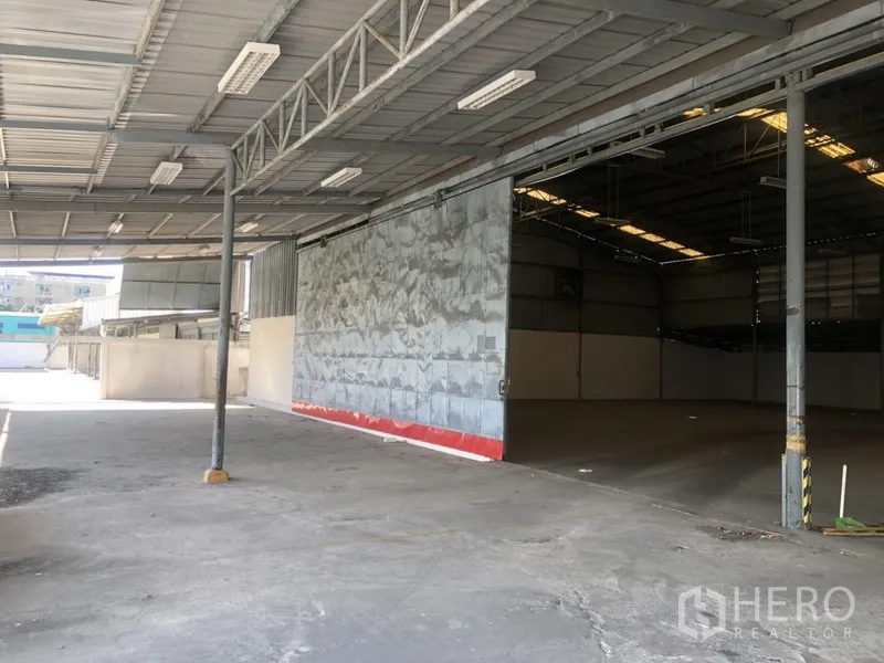 Warehouse for rent in Prawet, Bangkok - Covered loading bay with wide sliding metal door and truck access at the warehouse.