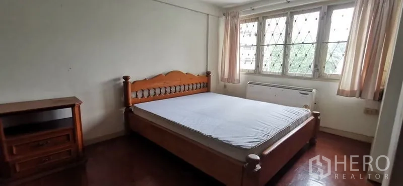 Townhouse for rent in Watthana, Bangkok - Bedroom with wooden bed, side cabinet and wide windows with security grilles