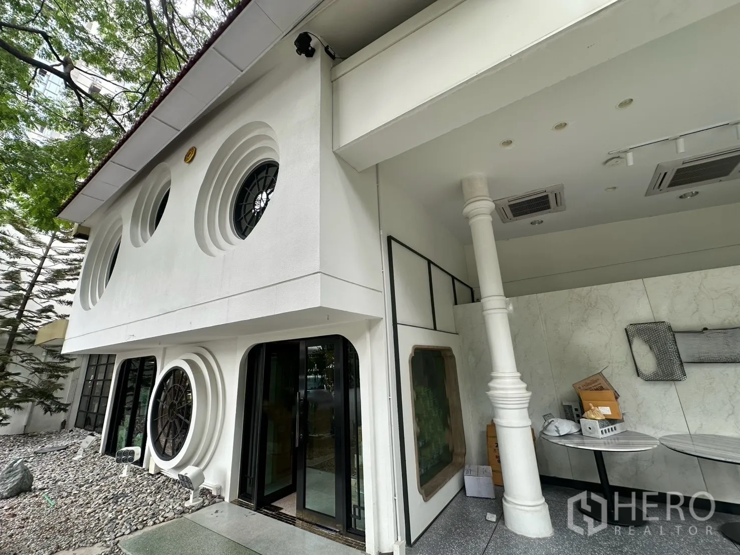 Detached House for rent in Watthana, Bangkok - Angled view of the white facade with multiple circular windows and porch.
