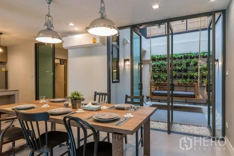 Townhouse for rent in Watthana, Bangkok - Dining room opening to courtyard with green wall and hanging bench swing.