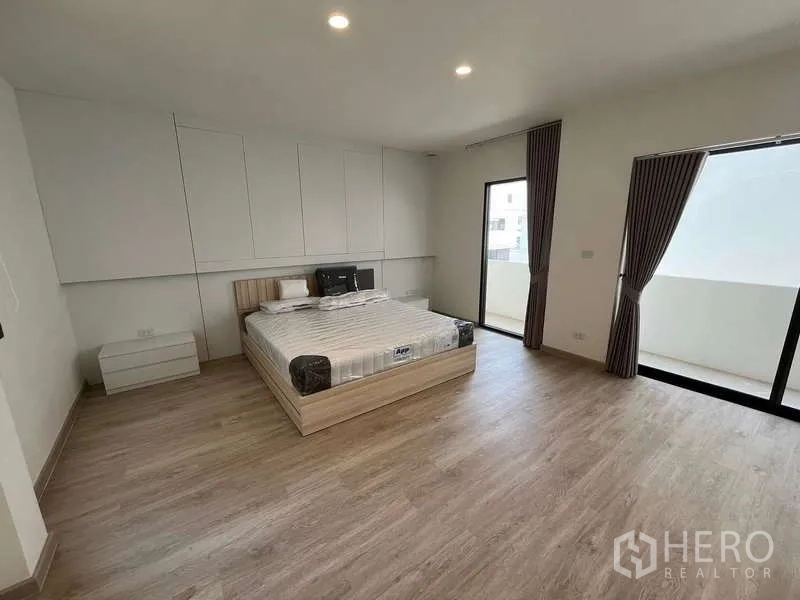 Townhouse for rent or sale in Don Mueang, Bangkok - Another bright bedroom with sliding doors to a balcony and built-in storage.