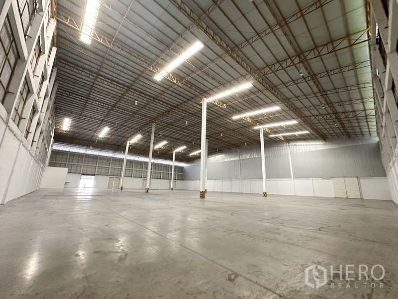 货栈 出租在Phra Nakhon Si Ayutthaya - 仓库内部开阔，钢桁架高顶与光滑混凝土地面。