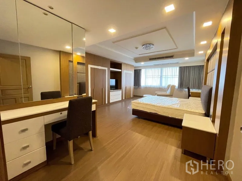 Condominium for rent in Watthana, Bangkok - Bedroom with mirrored dressing table, built-in wardrobes, and a seating nook.