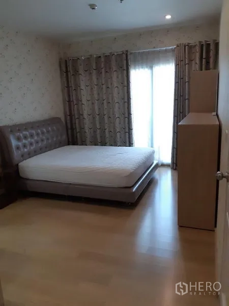 公寓 出租在Phaya Thai, Bangkok - 卧室配软包床、木地板与遮光窗帘，落地玻璃门通向阳台采光充足。