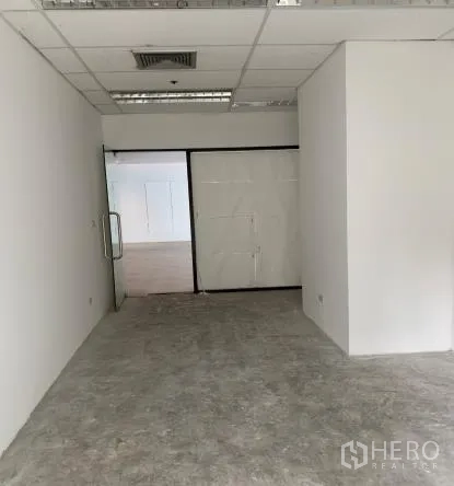 พื้นที่ขายปลีก ให้เช่า - ภายในพื้นที่ค้าปลีกเปล่า ผนังสีขาว ฝ้าทีบาร์ พร้อมช่องลมแอร์และประตูกระจก