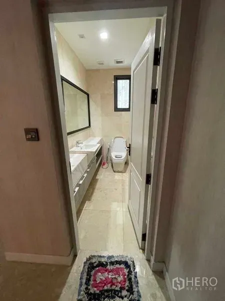Detached House for sale in Mueang Samut Prakan, Samut Prakan - Bathroom with double vanity, large mirror and toilet in neutral beige tiles.