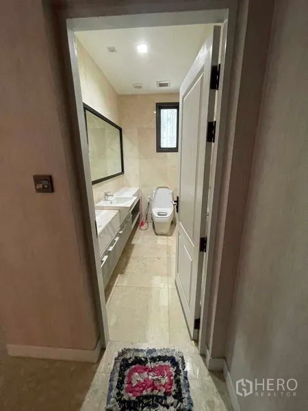 Detached House for sale in Mueang Samut Prakan, Samut Prakan - Bathroom with double vanity, large mirror and toilet in neutral beige tiles.