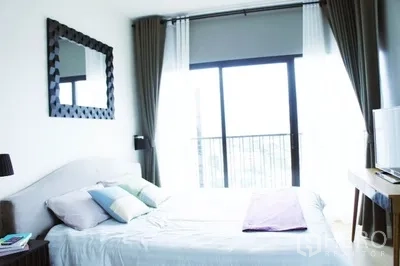 คอนโด ให้เช่าในPhaya Thai, Bangkok - ห้องนอนหลักพร้อมหน้าต่างบานใหญ่ กระจกเงาเหนือเตียง และโต๊ะวางของขนาดกะทัดรัด