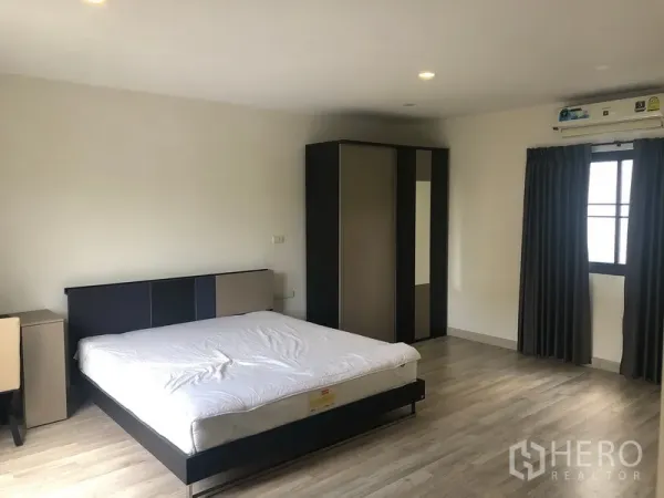Townhouse for rent in Saphan Sung, Bangkok - Spacious master bedroom with double bed, wardrobe, wood floors and window air-conditioning.
