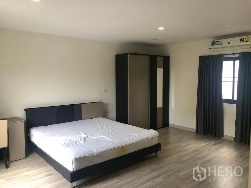 Townhouse for rent in Saphan Sung, Bangkok - Spacious master bedroom with double bed, wardrobe, wood floors and window air-conditioning.