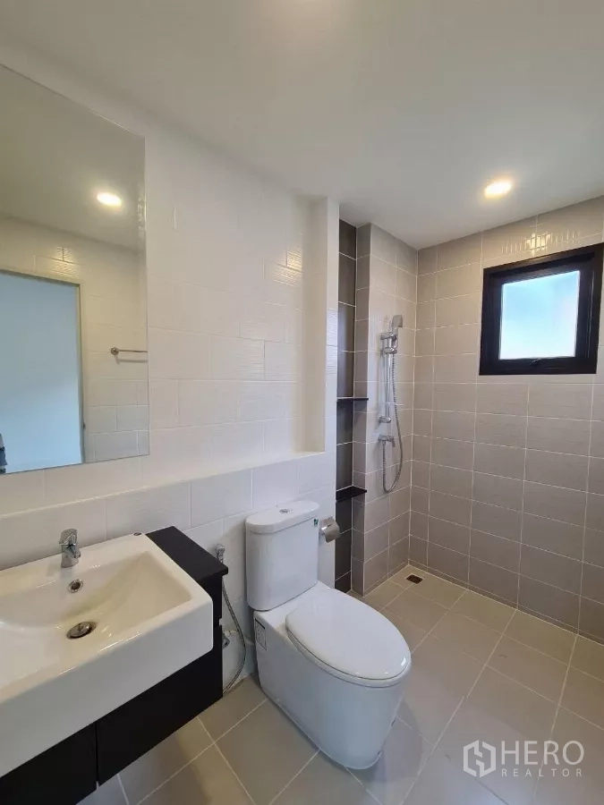 Detached House for sale in Samut Prakan - Modern bathroom with white sink, toilet, walk-in shower and a small window.