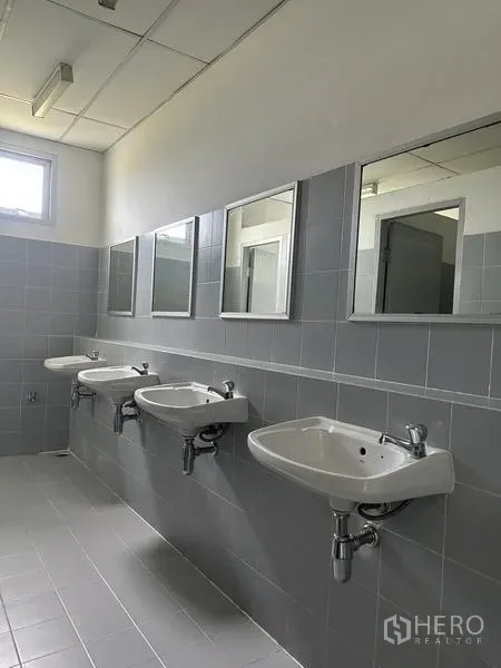 工厂 出租在Pathum Thani - 洗手间配三只壁挂式洗手盆、镜子与灰色瓷砖。
