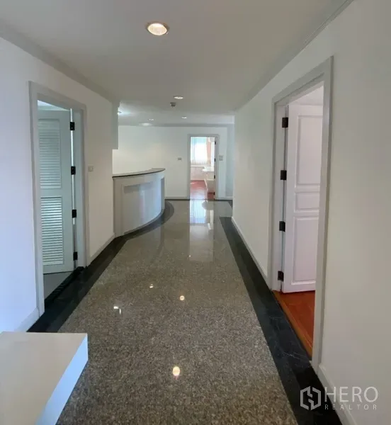 公寓 出租或出售在Watthana, Bangkok - 明亮公寓走廊，抛光花岗岩地面与白色墙面，多扇门通往各房间。
