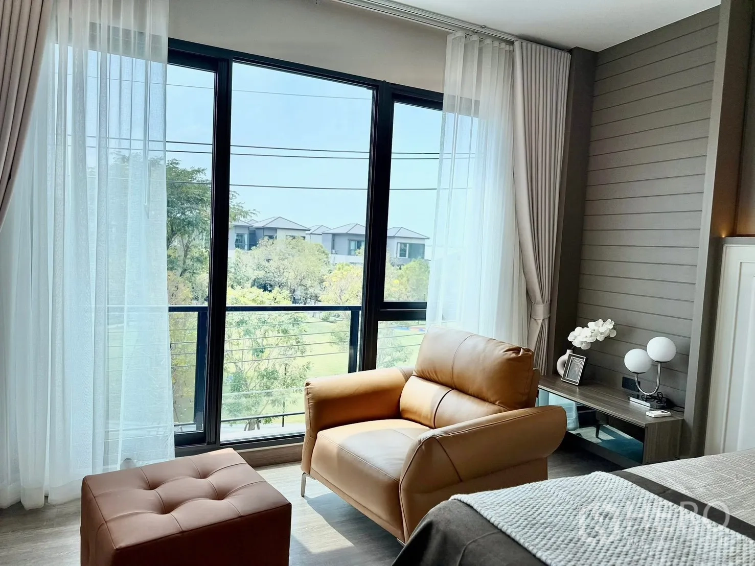 บ้านแฝด for rent in Bang Phli, Samut Prakan - มุมห้องนอนเก้าอี้หนังพร้อมสตูลข้างหน้าต่างสูง มองเห็นวิวสวน