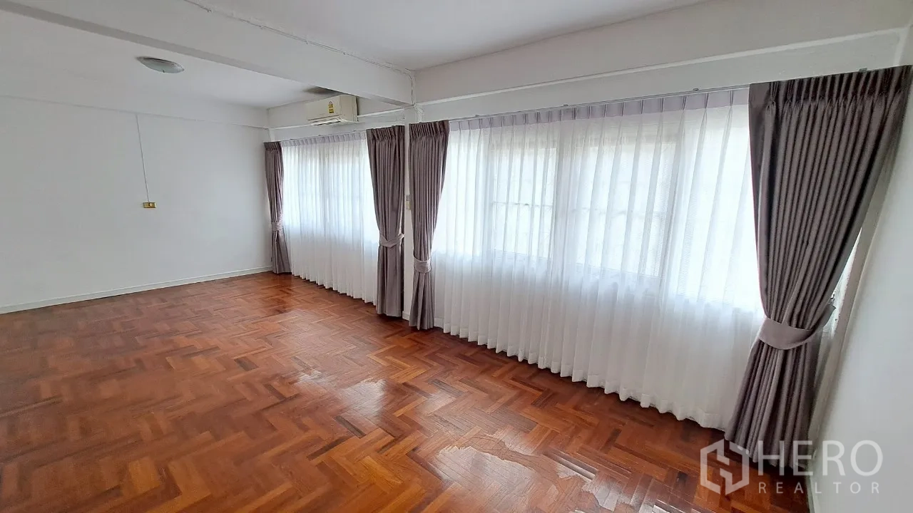 Townhouse for rent in Watthana, Bangkok - Corner view of sunlit master bedroom with wide windows and curtains.