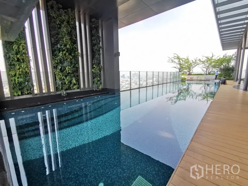 Condominium for rent in Khlong Toei, Bangkok - Rooftop infinity-edge swimming pool with city views and a vertical garden wall.